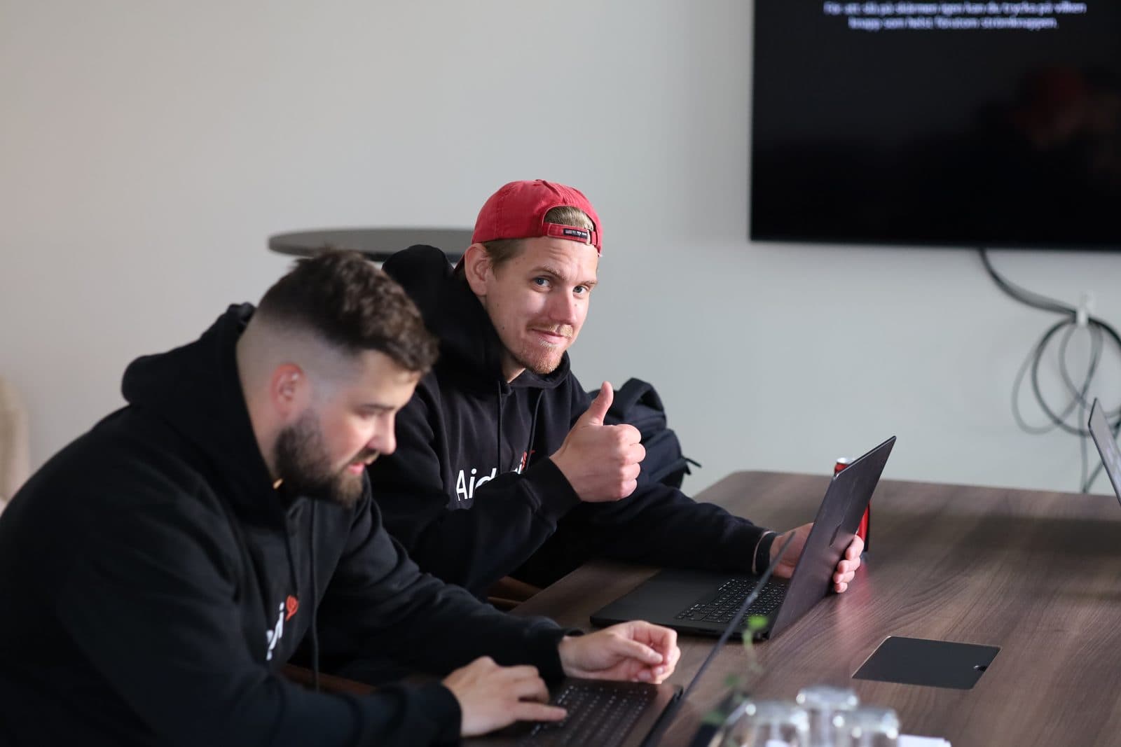 Två Aidoni-kollegor vid laptopen, tummen upp